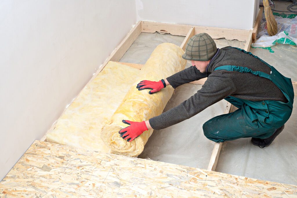 A worker insulates the floor with mineral wool
